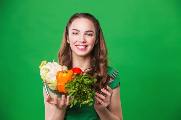 美しい女性の完全な新鮮で健康食品の食料品袋を保持しています。緑色の背景で — ストック写真