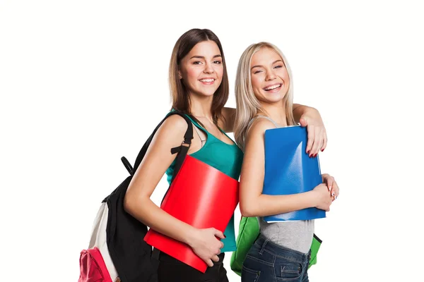 Két mosolygó diák lány iskolai hátizsákok a vállukon jelentő elszigetelt — Stock Fotó