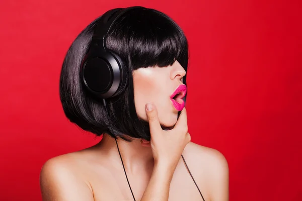 Woman listening to music on headphones enjoying a singing. Closeup portrait of beautiful girl with pink lips. Karaoke — Stock Photo, Image
