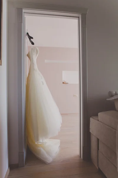 Elegant brudklänning hänger på en dörr väntar på ceremonin. Morgon bruden — Stockfoto