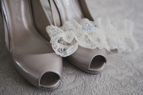 Közelkép a menyasszonyi esküvői cipő, harisnyatartó, textil alapon — Stock Fotó