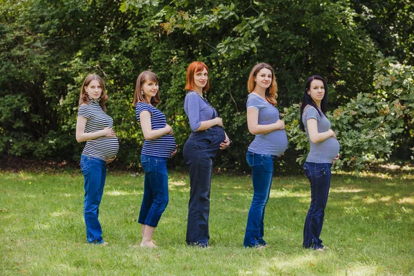 Cinque donne incinte con gli stessi vestiti all'aperto — Foto Stock