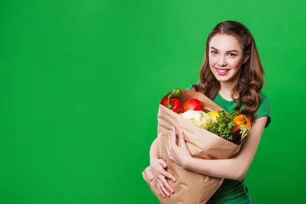 Bella donna che tiene una borsa della spesa piena di cibo fresco e sano. su sfondo verde — Foto Stock