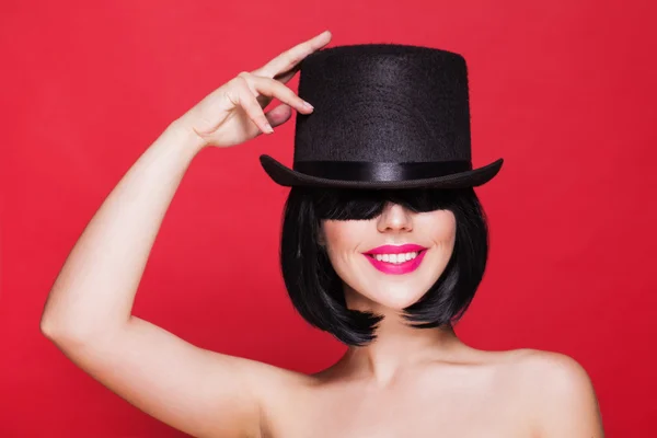 Fashion model in hat cylinder, on red background — Stock Photo, Image
