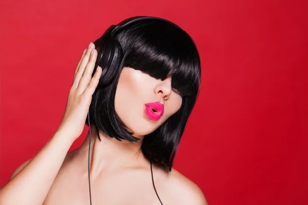 Kvinna lyssna på musik i hörlurar njuter en dans. närbild porträtt av vacker flicka med rosa läppar — Stockfoto