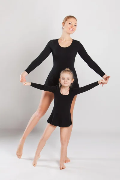 Mujer enseñando a bailar a una niña. madre e hija son gimnastas. sobre fondo blanco — Foto de Stock