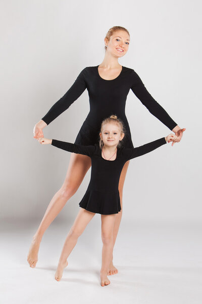 Woman teaching little girl dancing. mother and daughter are gymnastics. on white background