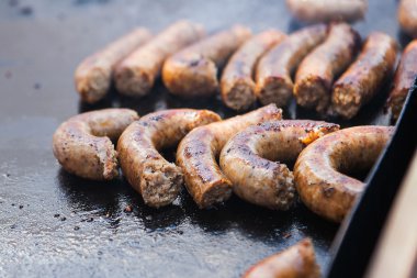 Domuz sosisi düz bir ızgarada pişirme görüntüsünü kapatmak