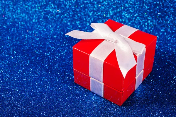Fényes, piros háttéren karácsonyi ajándék doboz — Stock Fotó