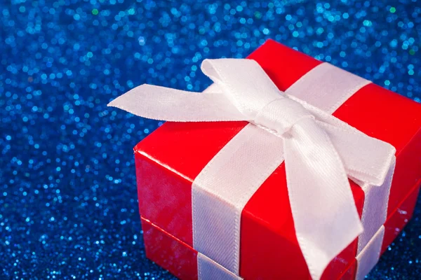 Caixa vermelha com presente de Natal no fundo azul brilhante — Fotografia de Stock