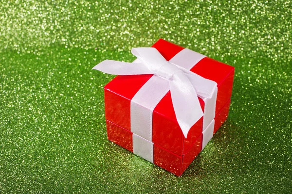 Karácsonyi ajándék doboz egy varázslatos csillogó fényes zöld háttér másol hely. — Stock Fotó
