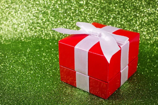 Karácsonyi ajándék doboz egy varázslatos fényes zöld háttér másol hely. — Stock Fotó