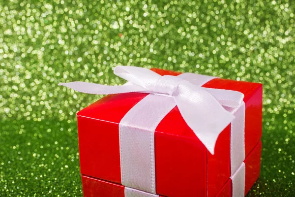 Close up of christmas gift against a magical glitter shiny green background with copy space. — Stock Photo, Image