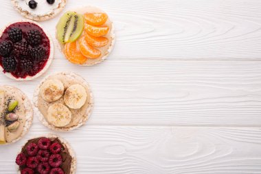 Tahta arka planda çeşitli malzemeli pirinç kekleri ve fotokopi alanı.