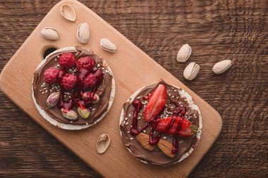 Çikolata ezmeli pirinç kekleri ve ahşap arka planda çilekli ahududular..