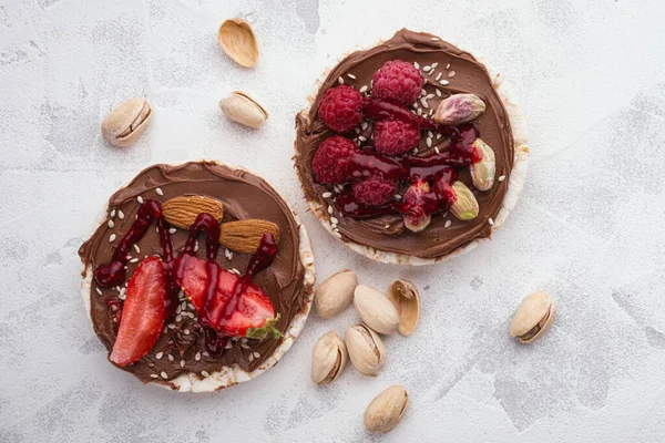 Rice cakes with chocolate-nut paste spread and berries and nuts top view.