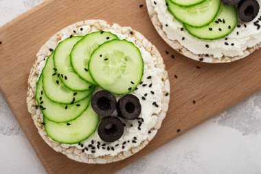 Pirinç keklerini krem peynirle kapat ve zeytinli salatalıkla kes..