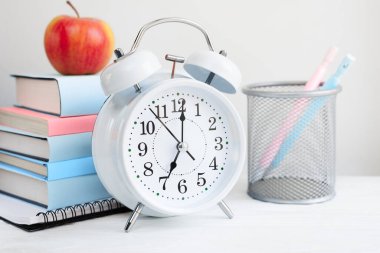 Masadaki çalar saat ve kitap yığını: okula dönüş konsepti.