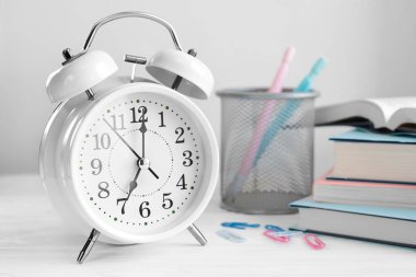 Saat yediyi ve kitapları gösteren çalar saat..