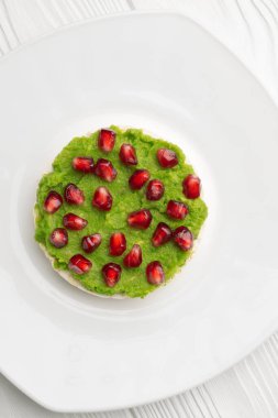 Pirinç keklerini avokado püresi ve nar tohumlarıyla dikey beyaz tabakta kapat..