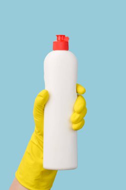 Lastik bir eldiven, mavi arka plan dikey çerçevesinde beyaz bir şişe tutar..