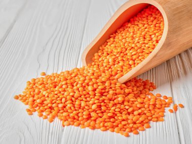 Ahşap bir masada kırmızı mercimek kepçesi.