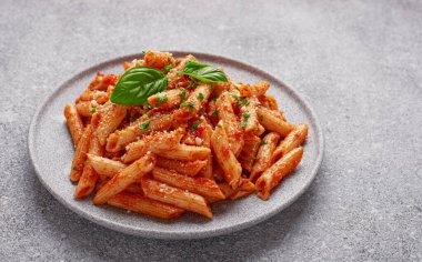 Gri arka planda Penne All 'arrabbiata makarnası olan bir tabağın yakın çekimi