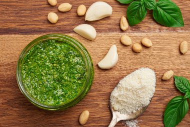 Cam kavanozda fesleğen ve ahşap arka planda malzemeler.