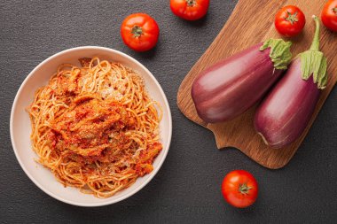Üst görünüm plakası EGPLANT PASTA Calabrese gibi ve karanlık arka planda yemek pişirmek için sebzeler