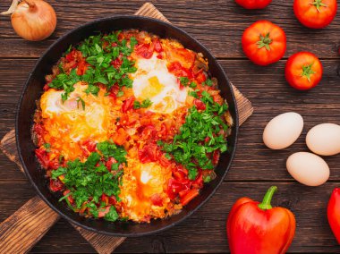 Ahşap bir arka plan manzarasında, kızartma tavasında taze pişmiş shakshuka.