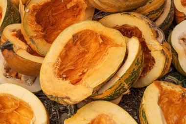 Pumpkin sections scattered across the ground reveal their bright orange insides after a harvest festival. The scene captures the essence of autumn in a rural setting, emphasizing nature's bounty.