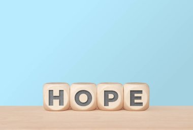 Açık mavi arkaplanda harf küpleriyle umut iyimserliği kavramı