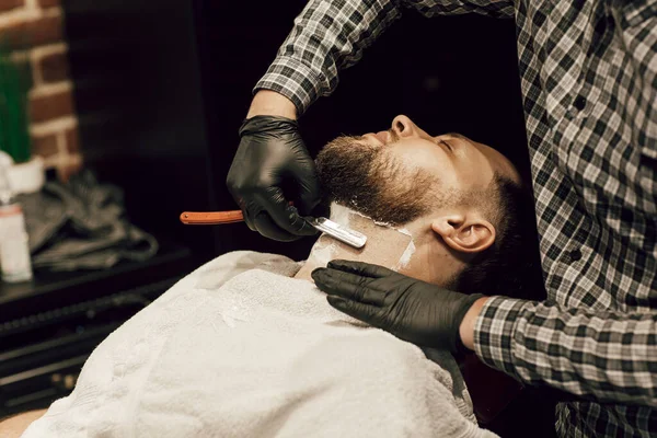 理发师在理发店刮胡子 用黑色手套把理发师的双手合拢在一起 给客人刮胡子 — 图库照片