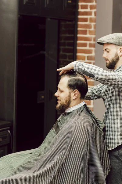 Homem Barbudo Jovem Recebendo Corte Cabelo Enquanto Sentado Cadeira Barbearia — Fotografia de Stock