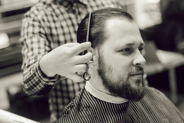 Homem Barbudo Jovem Recebendo Corte Cabelo Enquanto Sentado Cadeira Barbearia — Fotografia de Stock