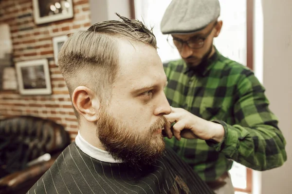 Homem Barbudo Jovem Recebendo Corte Cabelo Enquanto Sentado Cadeira Barbearia — Fotografia de Stock