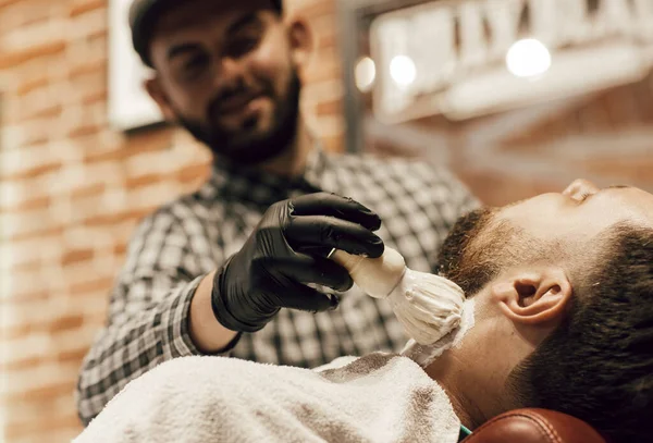 Corte de cabelo na barbearia. Cabeleireiro lubrifica a barba com gel de barbear — Fotografia de Stock