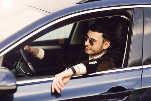 Young bussinesman in suit and black glasses driving his car. Bussines look. Test drive of the new car Stock Photo