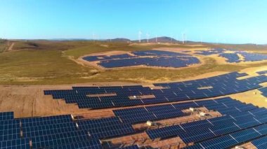 Güneş panelleri ve yenilenebilir enerji ile tarım. Arka planda rüzgar türbinleri olan İHA 'nın hava görüntüsü.