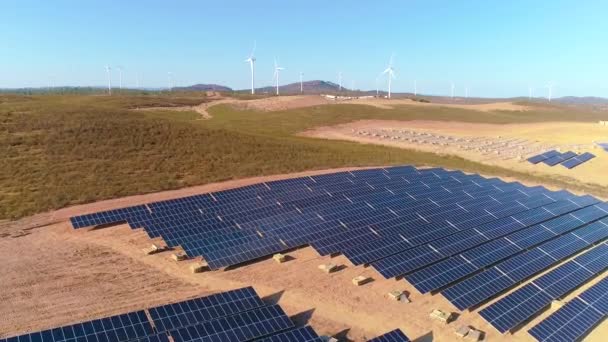 太陽光パネルと再生可能エネルギーで農場 背景に風力タービンを備えたドローンの空中ビデオ — ストック動画