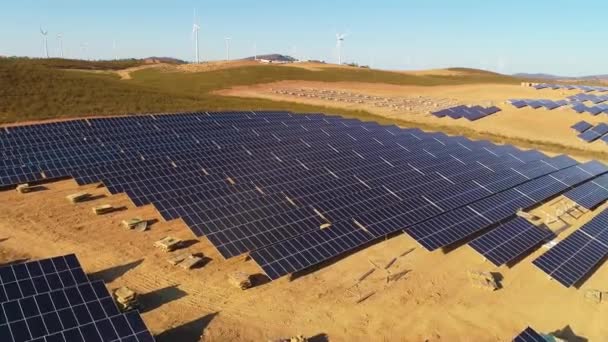 太陽光パネルと再生可能エネルギーで農場 背景に風力タービンを備えたドローンの空中ビデオ — ストック動画