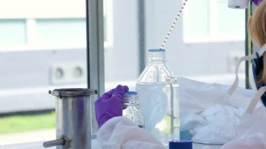 Mor eldivenli bilim adamı bir makinedeki tüpler ile test ve araştırma yapıyor. Sadece beyaz bir laboratuvarda bulunan mikrobiyologların ellerini görebiliyoruz. Yakın çekim görüntüsü. Bilim deneyi konsepti