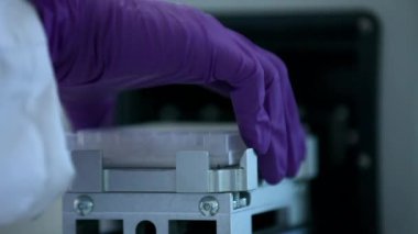 Mor eldivenli bir bilim adamı laboratuarda örnek tüplerle test ve araştırma yapıyor. Beyaz labaratuvarda bulunan bir mikrobiyologun sadece ellerini görebiliyoruz. Yakın çekim bilim deneyi konsepti.