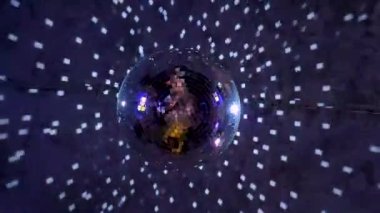 Mavi ışıklı, dönen ve beyaz ışıklarla yanıp sönen karanlık bir odada tavandan sarkan bir disko topu..