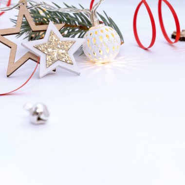 Beyaz toplardan oluşan çelenkler, beyaz arkaplanda köknar dalları ve kırmızı kurdeleler bulunan ahşap yıldızların Noel kompozisyonu