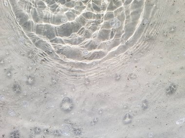 Su ve kumun doğal arka planında yüzeyde yuvarlak çizgiler var.