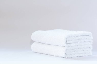 Aydınlık bir arkaplanda iki beyaz terry havlu.