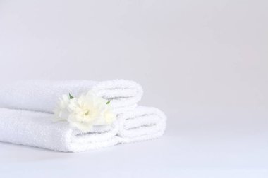 Arkaplanda yasemin çiçeği olan üç beyaz terry havlusu.