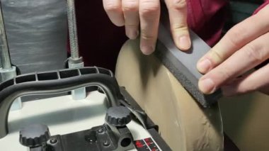 Bir adam ince taneli bir bilek taşını öğütücüdeki bir çubukla dümdüz eder..