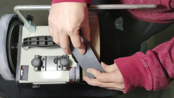 A man flattens a fine-grained whetstone with a bar on a water grinder. — Vídeo de stock